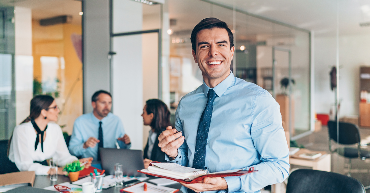 man standing in office in front of coworkers